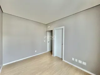 Esta é uma vista de um corredor interno com paredes cinzas e piso de madeira clara.