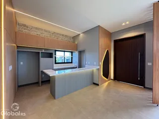 A cozinha moderna possui armários de madeira e uma ilha com bancada clara.