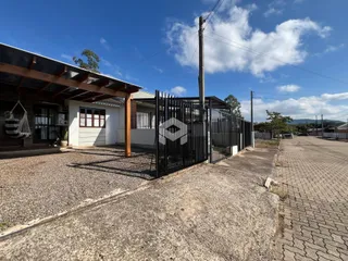 Vista externa da propriedade com cerca de metal e estrutura de madeira.