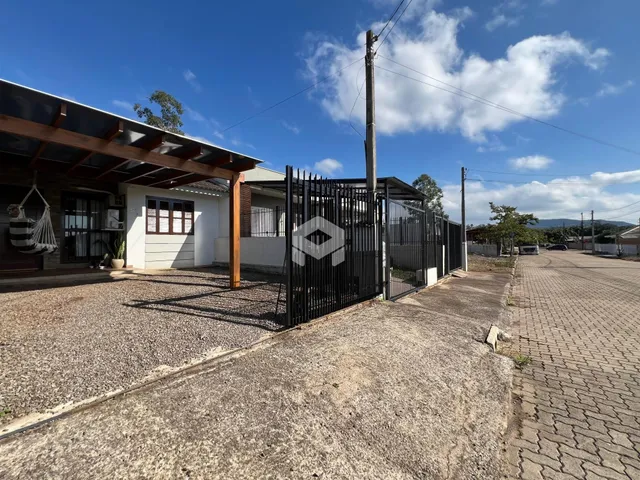 Vista externa da propriedade com cerca de metal e estrutura de madeira.
