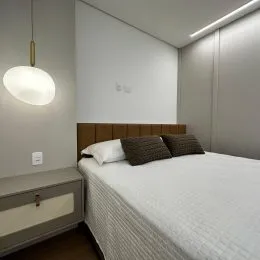 Quarto com cama de casal e paredes brancas.