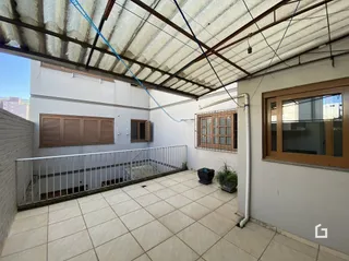 Vista externa de uma área pavimentada com piso de cerâmica e grade de metal.