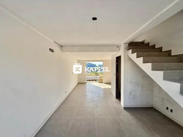 Corredor interno com piso de cerâmica e escadaria de concreto em uma residência.