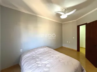 Quarto com cama e piso de madeira clara.