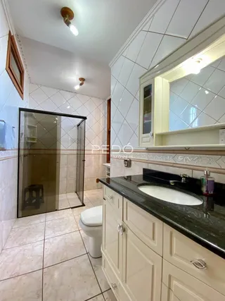 Foto de um banheiro com box de vidro e revestimento cerâmico.