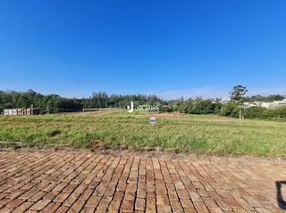 Vista de campo com grama e piso de tijolos no exterior de uma propriedade.