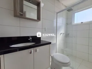 Banheiro com revestimento branco e bancada escura.