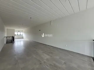 Vista de um corredor interno com teto de painéis brancos e piso de concreto polido.