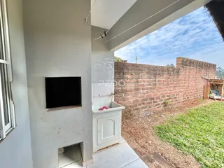 Vista da fachada de uma residência com parede de tijolos aparentes e gramado.
