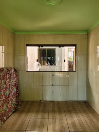 Interior de uma sala com paredes verdes e piso de madeira clara.