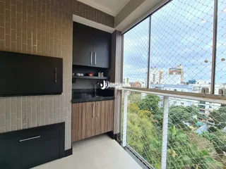 Vista interna de uma cozinha com armários escuros e grande janela.