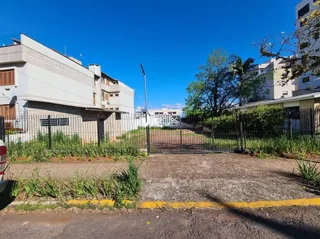 Vista externa de uma propriedade com cerca e vegetação no primeiro plano.