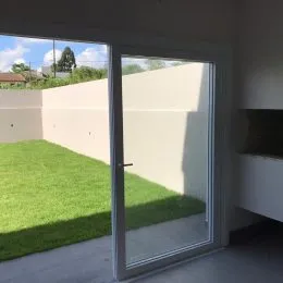 Vista de um cômodo interno com acesso a um gramado verde.