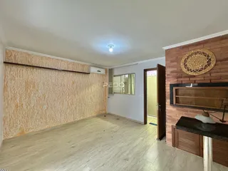 Ambiente interno de uma sala com piso de madeira e parede texturizada.