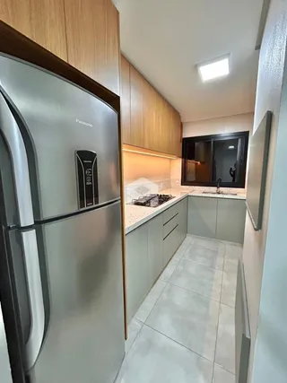 Vista da cozinha com armários e eletrodomésticos em um imóvel.