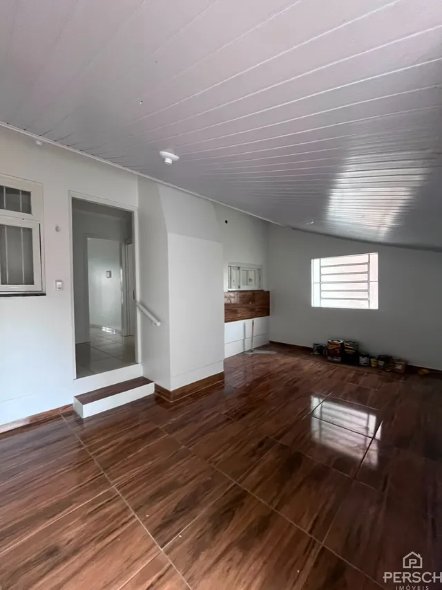 Ambiente interno com piso de madeira escura e teto alto em uma residência.