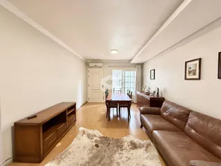 Uma sala de estar com piso de madeira e sofá de couro.
