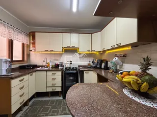 Vista interna de uma cozinha com armários brancos e bancadas de granito.
