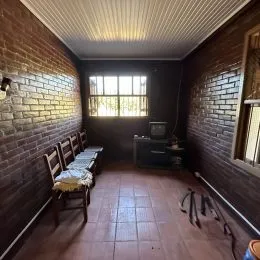 Foto de um corredor interno com paredes de tijolo aparente e piso de madeira.