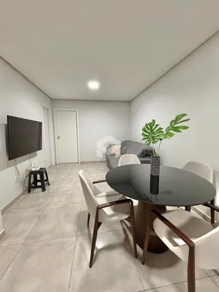 Uma sala de estar interna com sofá e mesa de jantar.