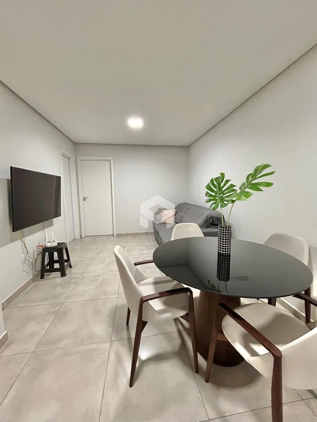 Uma sala de estar interna com sofá e mesa de jantar.