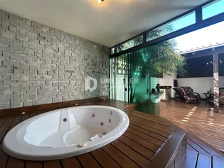 Uma banheira oval branca está instalada sobre um piso de madeira.