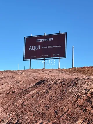 Placa de publicidade de imóvel em terreno com solo irregular.