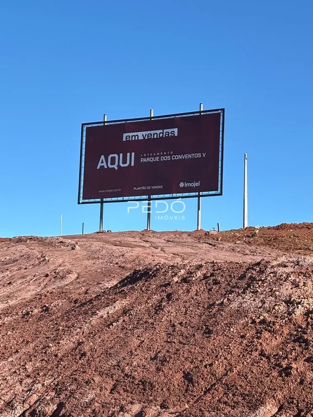 Placa de publicidade de imóvel em terreno com solo irregular.