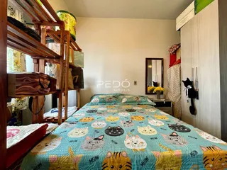 Quarto com cama decorada e estantes de madeira em um imóvel no Brasil.