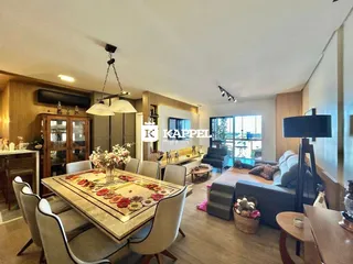 Sala de estar e jantar com mesa de madeira e sofá em ambiente iluminado.