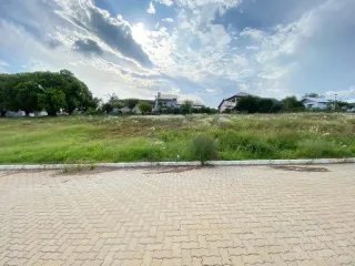 Vista externa de um terreno gramado com vegetação ao fundo.
