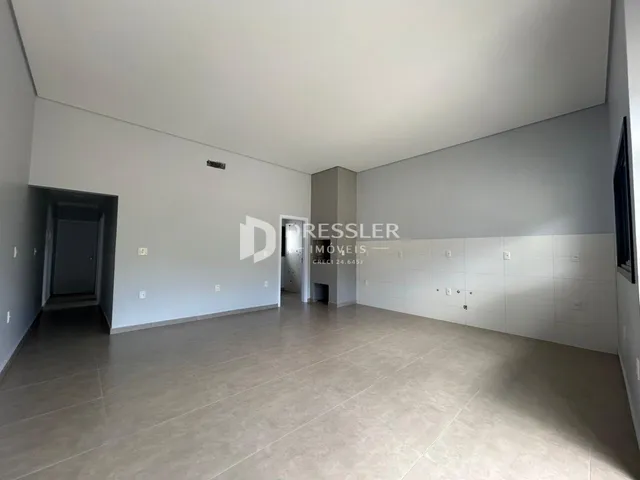 Imagem de um ambiente interno amplo com paredes brancas e piso de cerâmica.