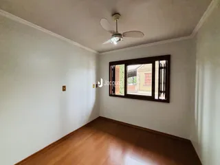 Vista interna de um ambiente com piso de madeira e parede branca.
