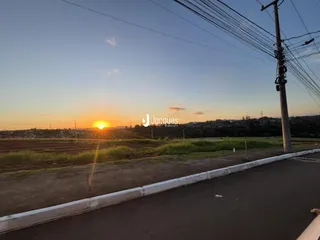 Paisagem de campo ao pôr do sol com uma estrada no primeiro plano.