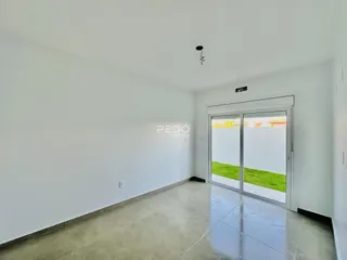 Sala de estar ampla com piso de porcelanato claro e porta de vidro.