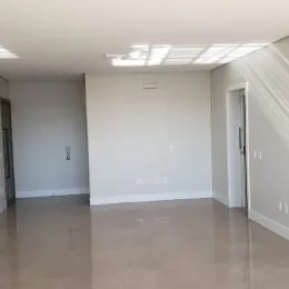 Ambiente interno amplo e vazio com piso claro e paredes brancas.