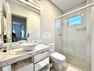 Banheiro moderno com revestimento de azulejos brancos e bancada de mármore.