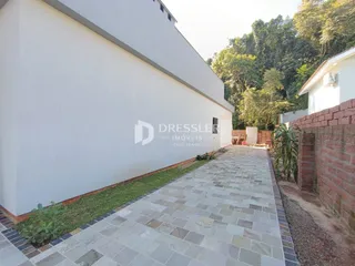 Fachada de uma residência com calçada de pedras e jardim.