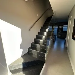 Corredor com escadaria metálica escura em um apartamento.