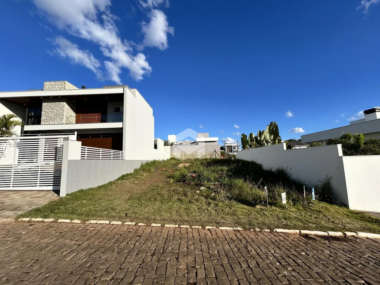 Fachada de uma casa moderna em Lajeado, Brasil, com muro branco e gramado.