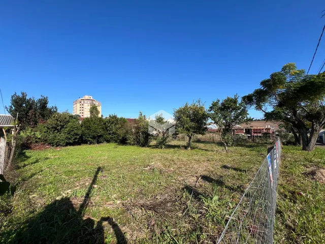 Vista externa de um terreno gramado com cerca e vegetação.