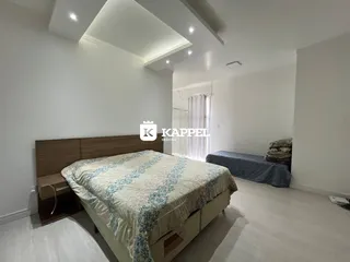 Quarto com cama de madeira e paredes brancas.