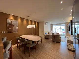 Uma sala de jantar com mesa redonda e cadeiras em um ambiente com painéis de madeira.