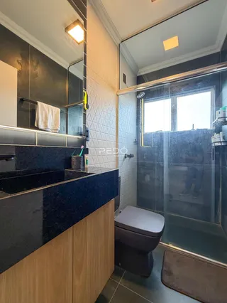 Banheiro com revestimento de azulejos brancos e bancada escura.