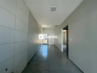Corredor interno de um imóvel com paredes claras e piso de concreto.