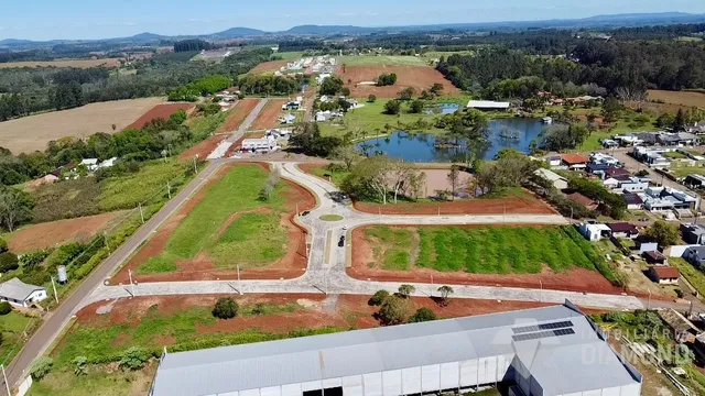 Vista aérea de uma propriedade rural com áreas verdes e um corpo d'água.
