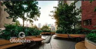 Vista de um pátio externo com vegetação e mobiliário de jardim.