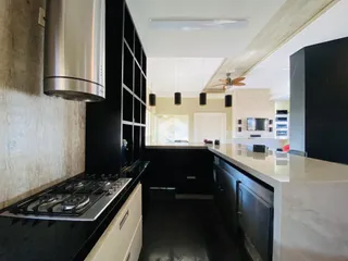 Cozinha moderna com armários escuros e bancadas claras.