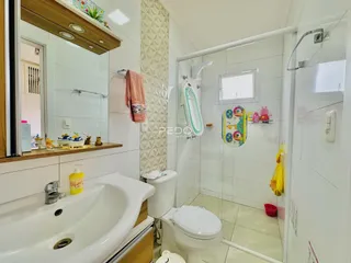 Foto de um banheiro com revestimento cerâmico e box de vidro.