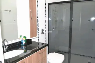 Foto de um banheiro com box de vidro e pia de granito.